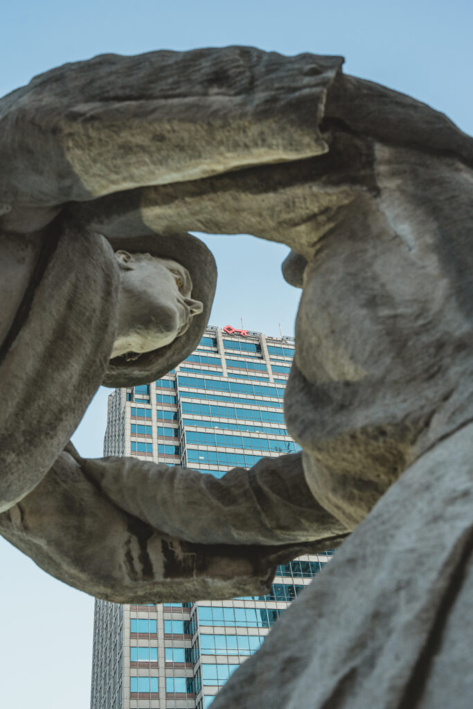 A photo of the Key Bank building framed between two statues.