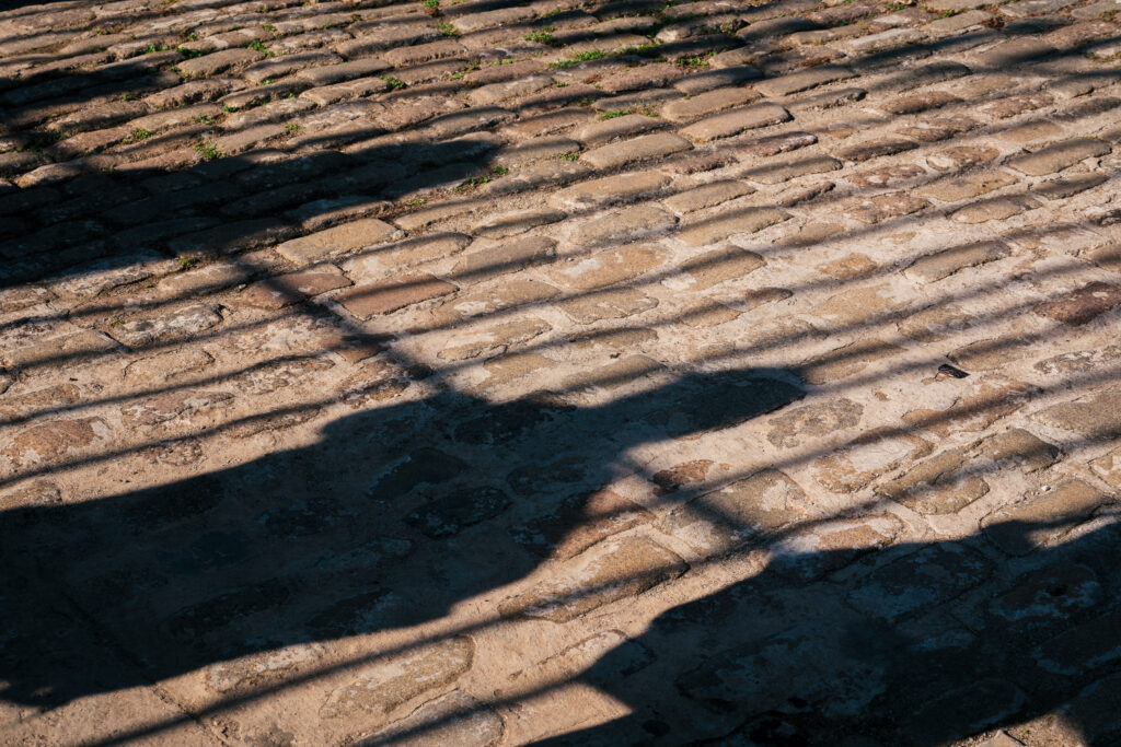 Shadows of bars and people on the brick street in Havana, Cuba.