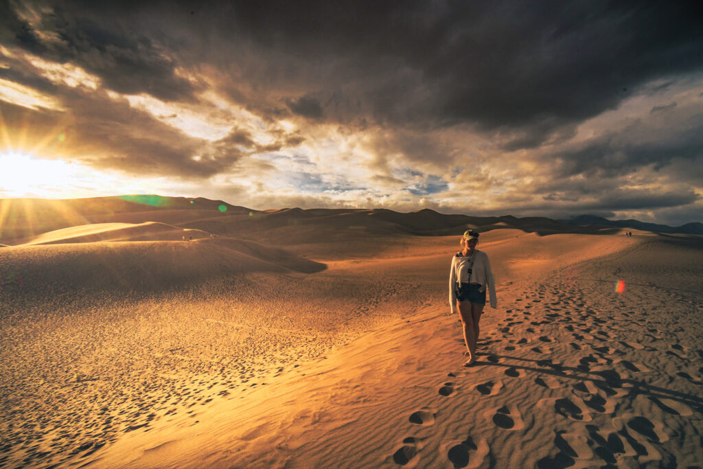 Sunset and a lone woman walking at the great sand dunes national park.