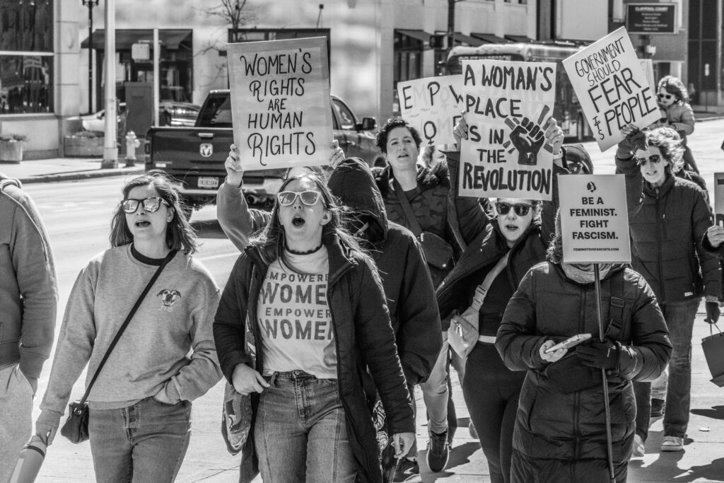 No kings protest women carrying protest signs.